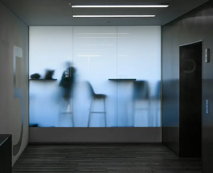 Meeting room behind frosted glass with figures blurred